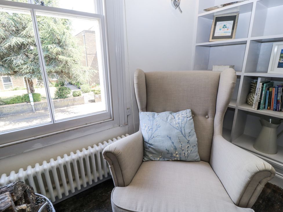 A reading nook with an armchair and bookshelf at Delightful Dorset House By Wareham River