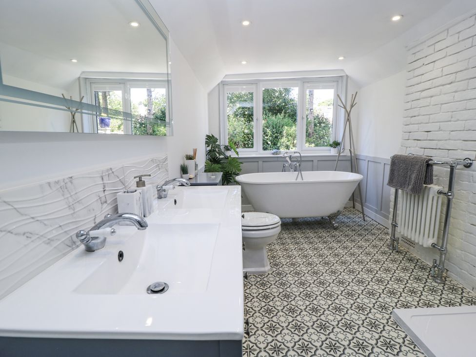 A bathroom with a bathtub, sink, and toilet at Delightful Dorset House By Wareham River in Wareham