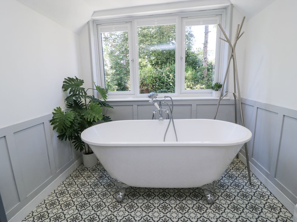 A bathroom with a bathtub and plants at Delightful Dorset House By Wareham River in Wareham