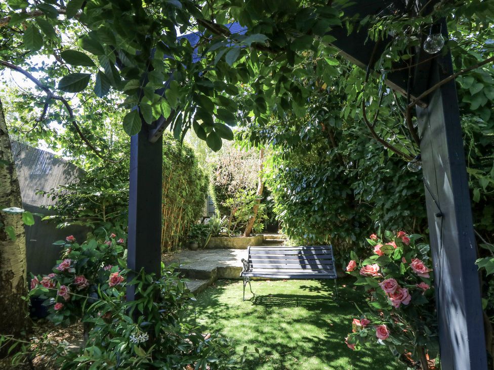 A garden with a swing and flowers at Delightful Dorset House By Wareham River in Wareham