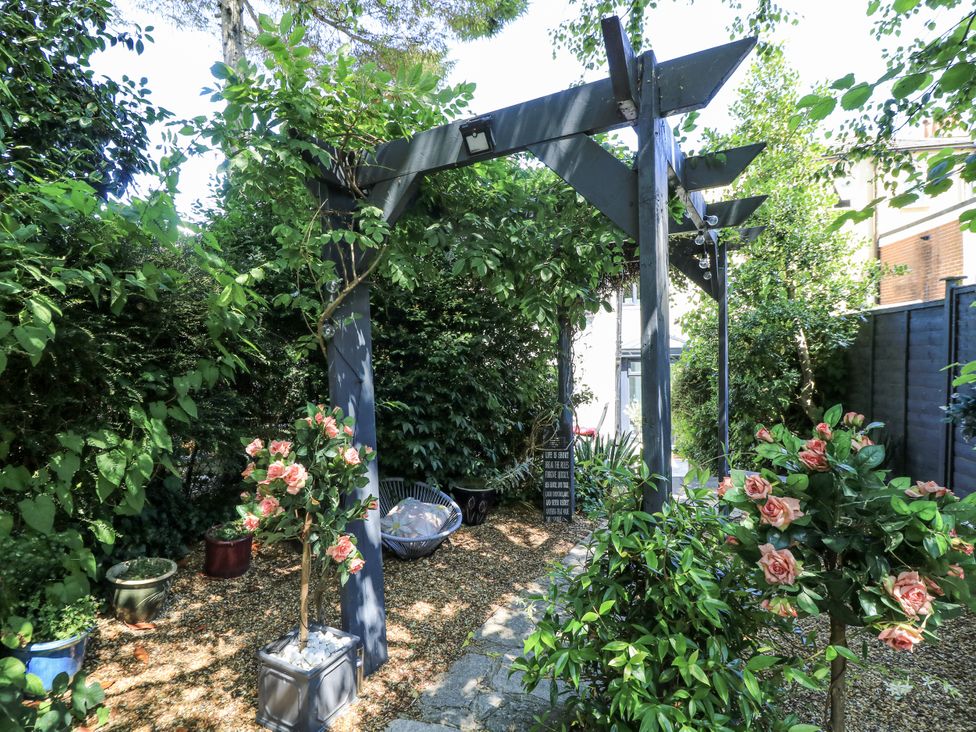 A garden with an archway surrounded by flowers and gravel at Delightful Dorset House By Wareham River, Wareham