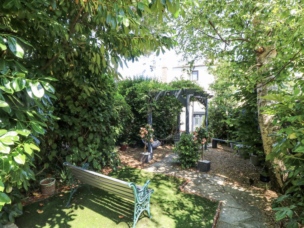 A garden with a bench and a pergola at Delightful Dorset House By Wareham River in Wareham