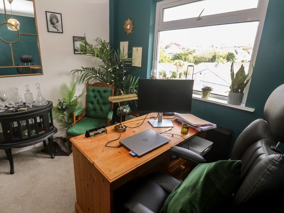 A home office with a desk, computer monitor, and potted plants at 4 Cardell Way, Newquay