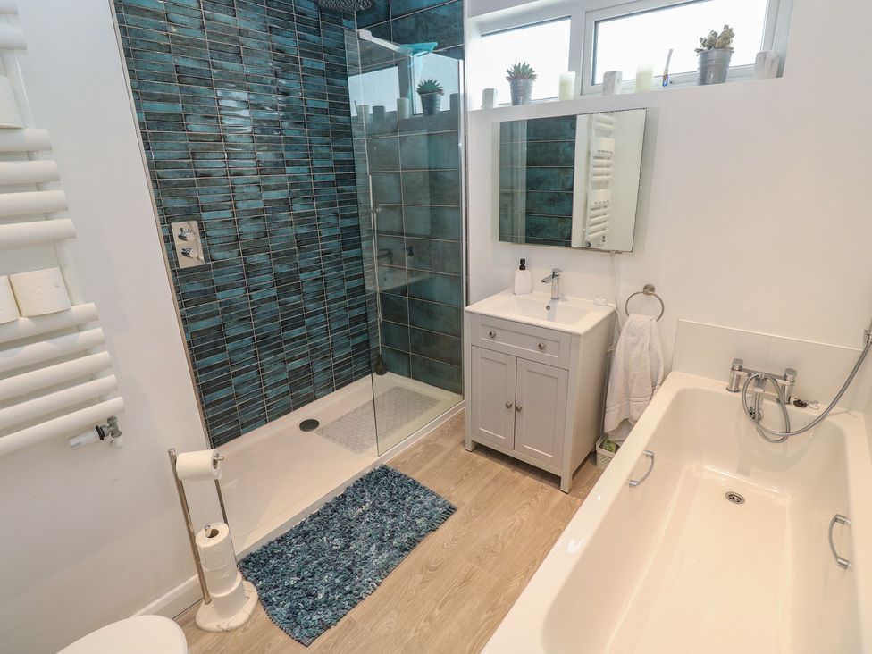 A bathroom with a bathtub, shower, and sink at 4 Cardell Way in Newquay