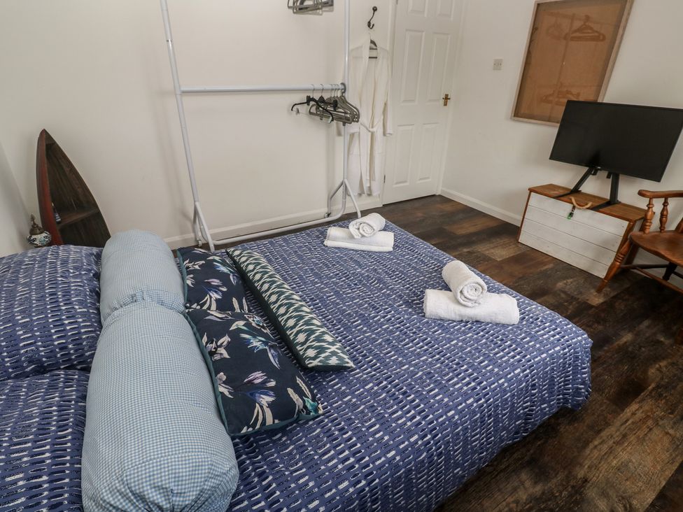 A bedroom with a bed, towels, tv, and clothes rack at 4 Cardell Way, Newquay