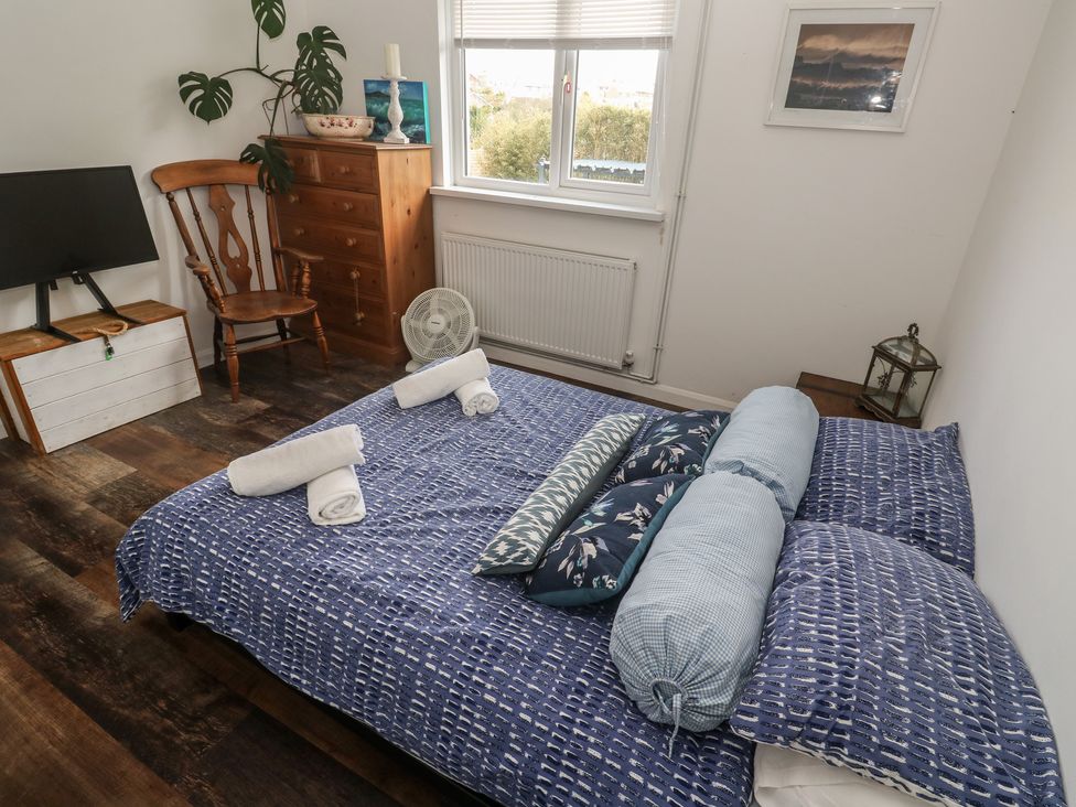 A bedroom with a bed, television, dresser and chair at 4 Cardell Way in Newquay