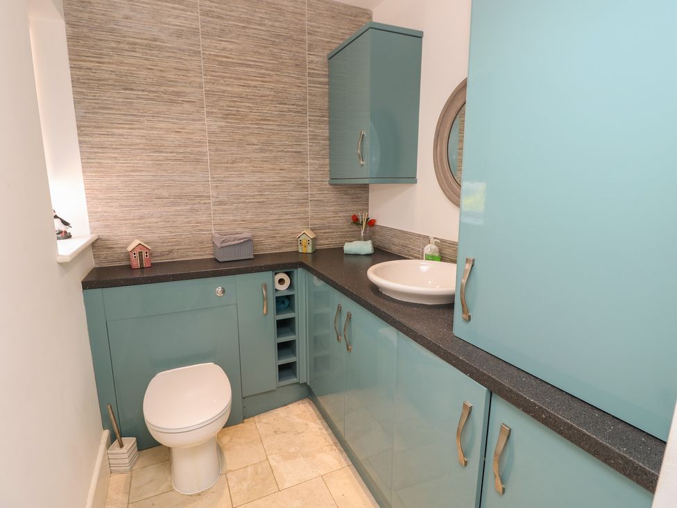 A bathroom with a sink, toilet, and storage at Guildford Farmhouse in Ryde