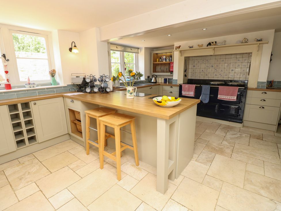 A kitchen with an island and bar stools at Guildford Farmhouse in Ryde