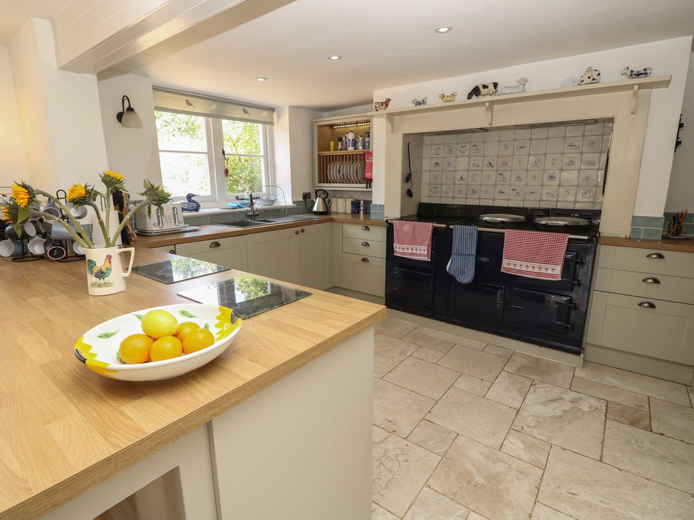A kitchen with a stove, sink, and cabinets at Guildford Farmhouse in Ryde