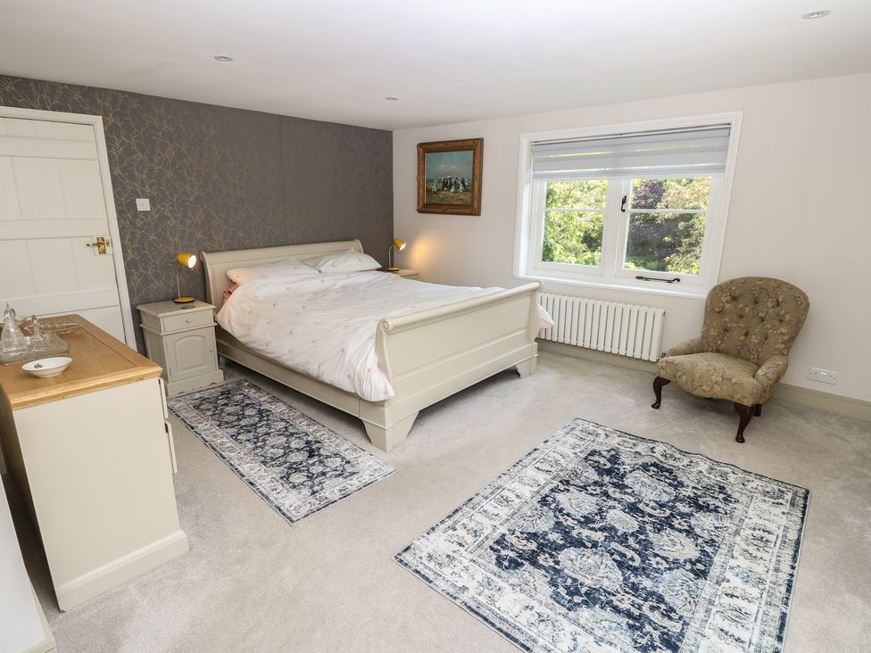 A bedroom with a bed and armchair at Guildford Farmhouse in Ryde