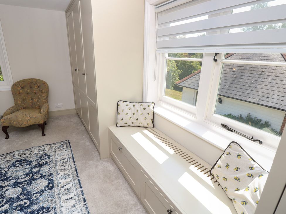 A bedroom with a window seat and armchair at Guildford Farmhouse in Ryde