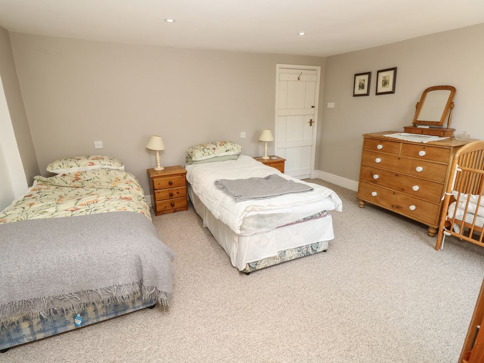 A bedroom with two beds and a crib at Guildford Farmhouse in Ryde