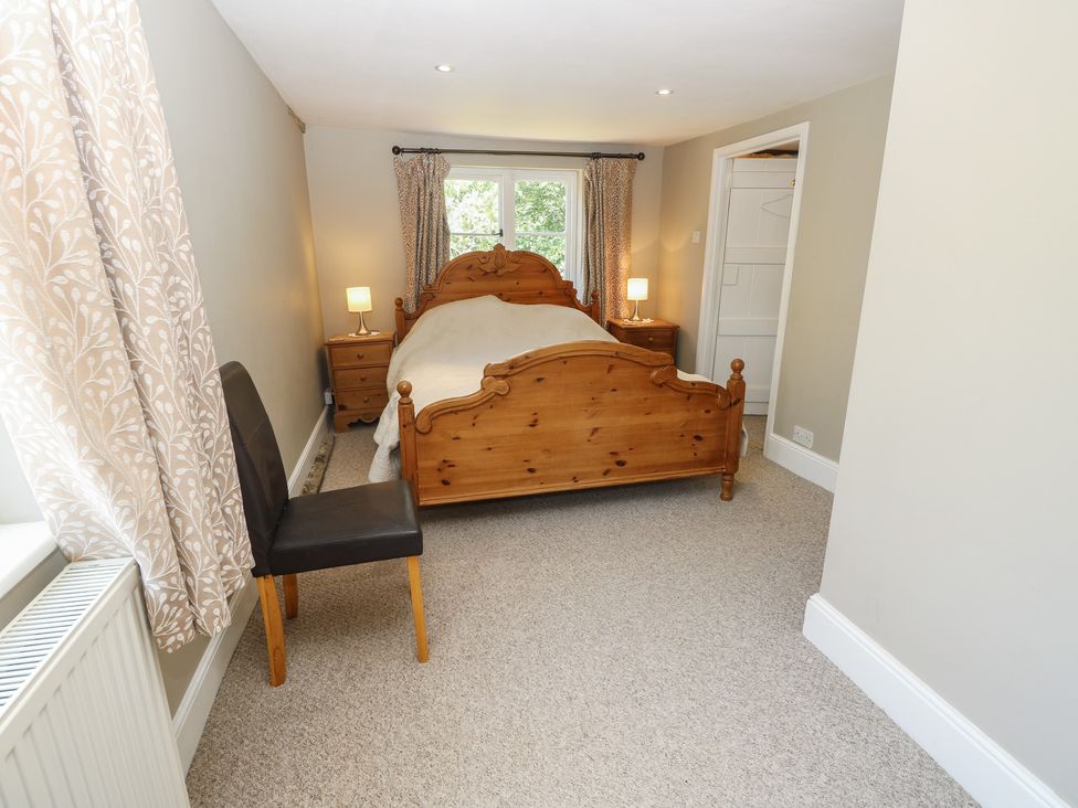 A bedroom with a wooden bed and nightstand at Guildford Farmhouse in Ryde
