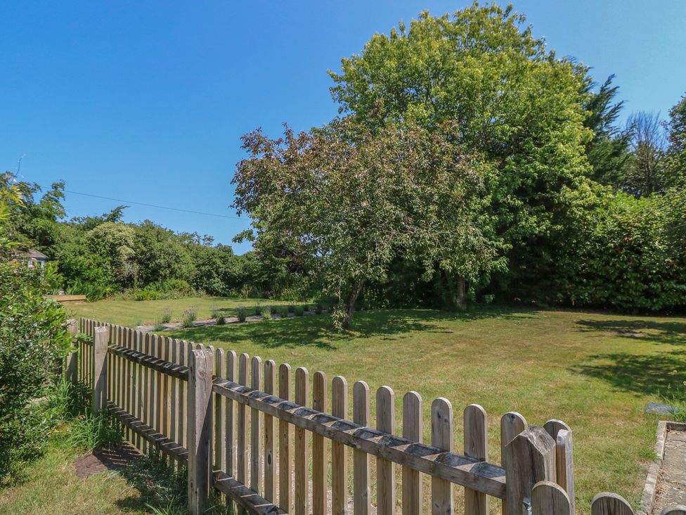 A garden with a wooden fence and trees at Guildford Farmhouse in Ryde