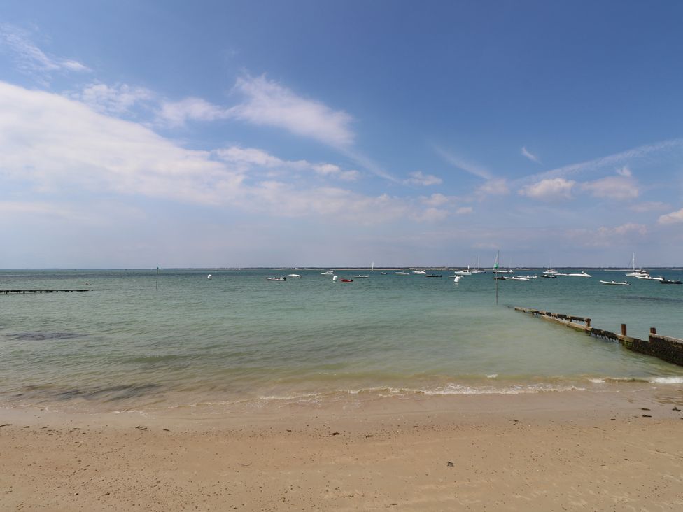 A beach scene with water, boats, and a pier at Guildford Farmhouse in Ryde
