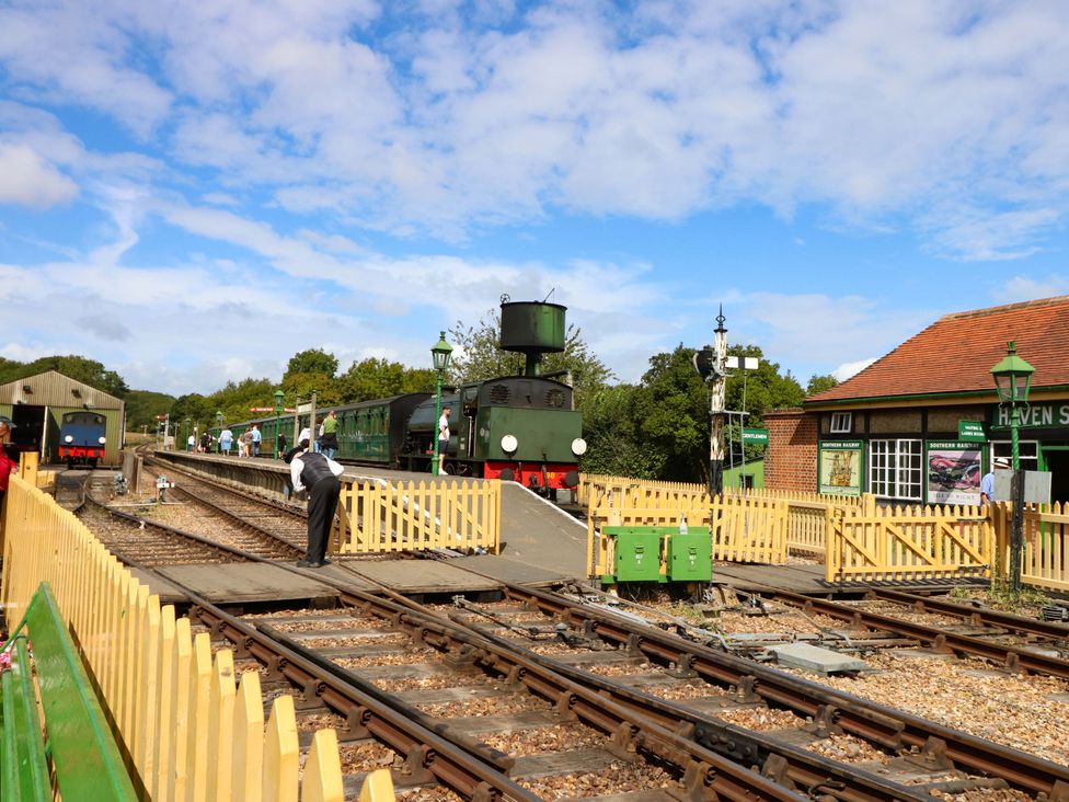 A steam train at a train station with people and a building at Havenstreet near Newport, Isle Of Wight