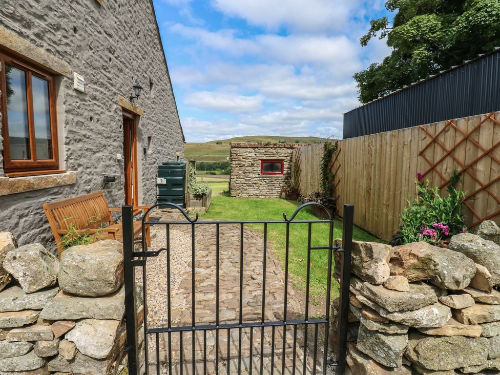 A garden with a stone wall and gate at Middlefell View Cottage in Alston