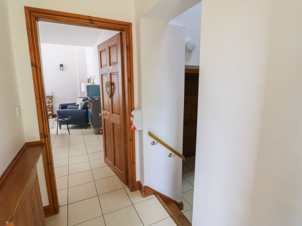 A hallway with a staircase and a door leading to a living room at Middlefell View Cottage Alston