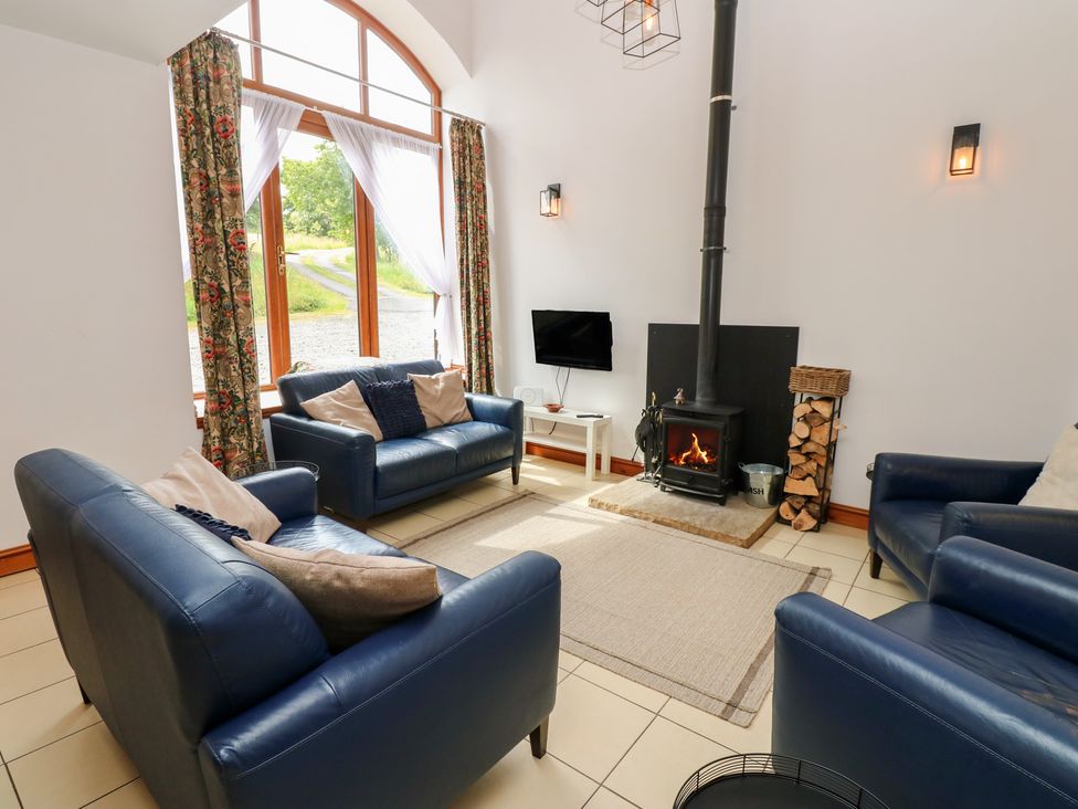A living room with a wood stove and sofa seating at Middlefell View Cottage in Alston