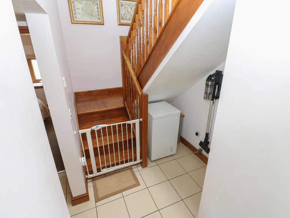 A hallway with a staircase and a vacuum cleaner at Middlefell View Cottage Alston