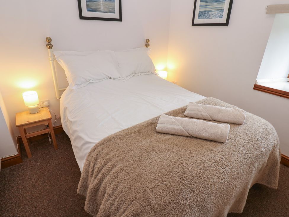A bedroom with a bed, bedside table, and towels at Middlefell View Cottage in Alston