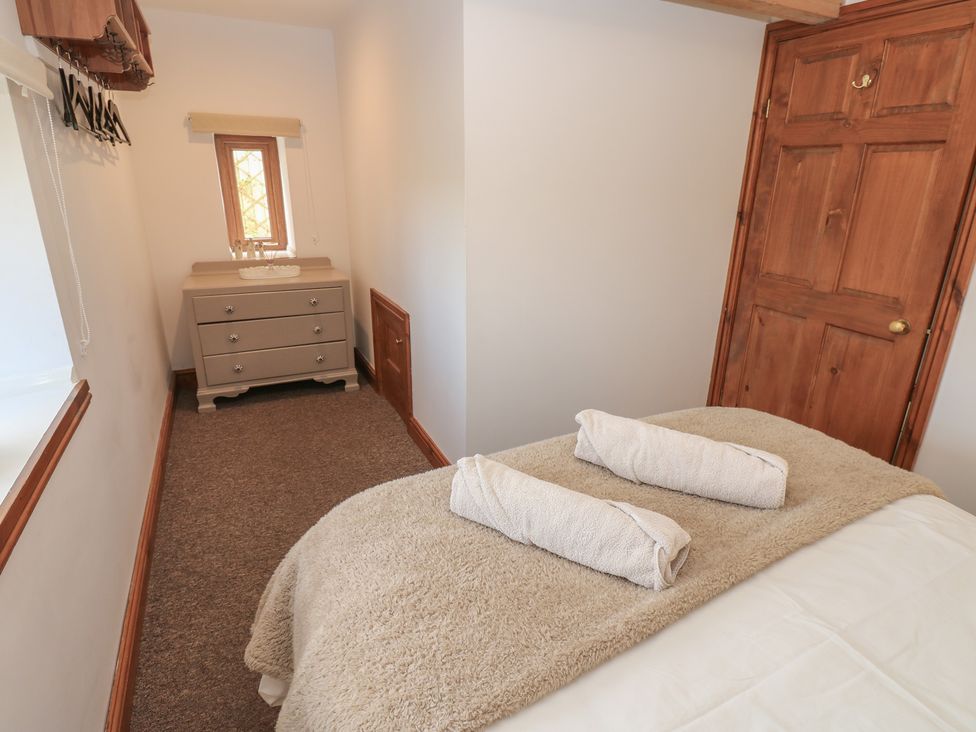 A bedroom with a bed and dresser at Middlefell View Cottage in Alston