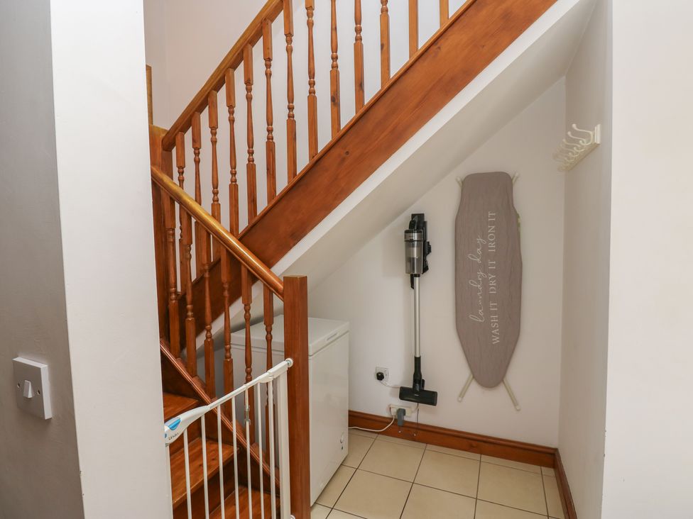 A hallway with a staircase and washing machine at Middlefell View Cottage in Alston