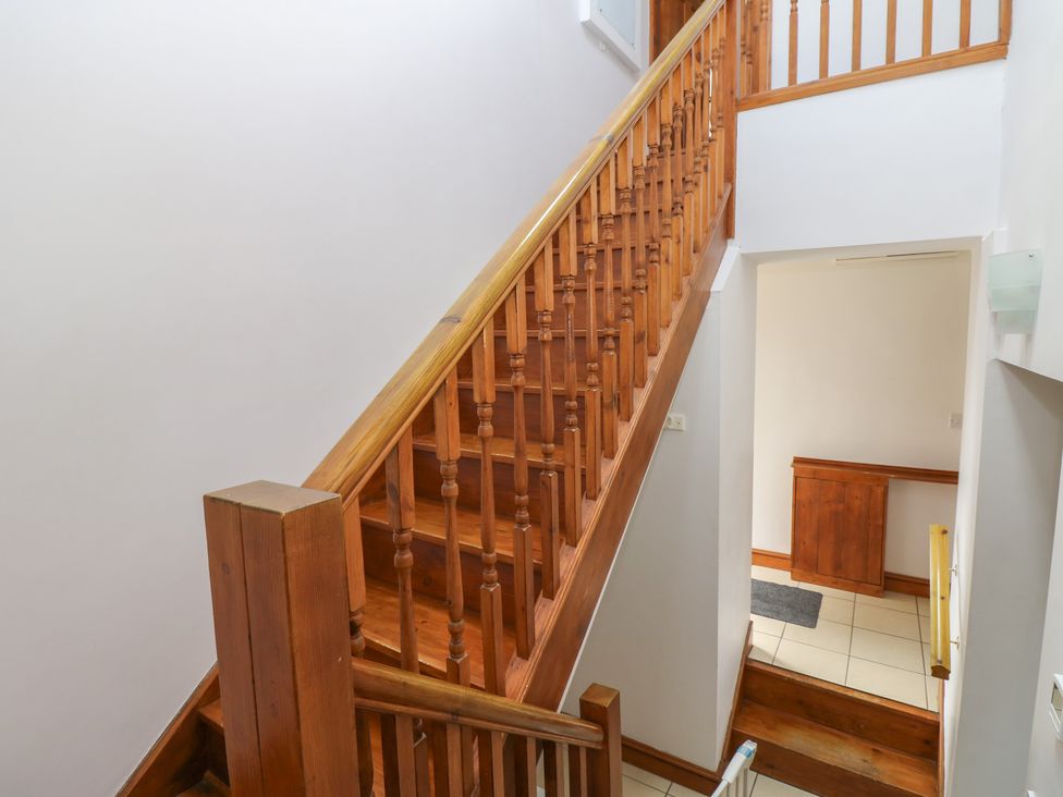 A staircase with wooden handrail and tiled floor at Middlefell View Cottage in Alston