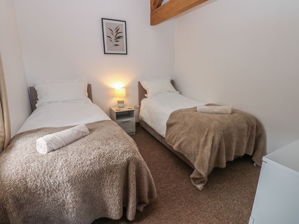 A bedroom with twin beds and a nightstand at Middlefell View Cottage Alston