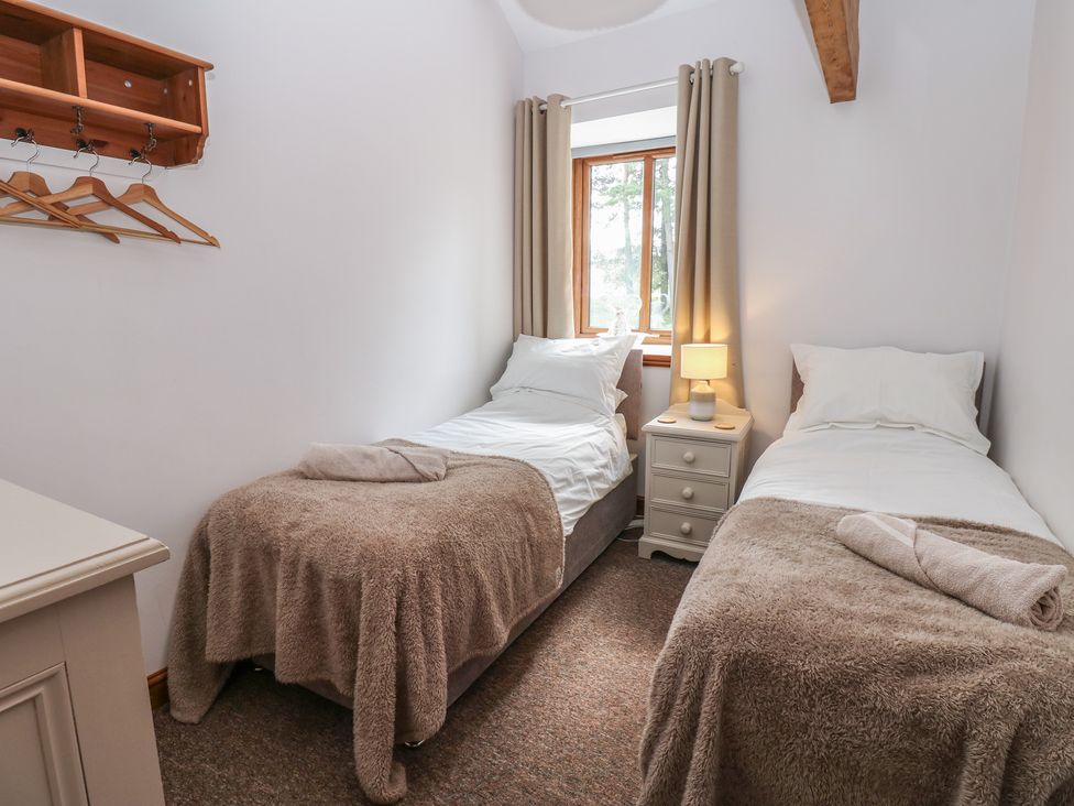 A bedroom with two beds and a window at Middlefell View Cottage, Alston