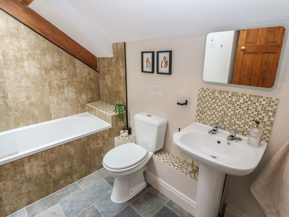 A bathroom with a bathtub, toilet, and sink at Middlefell View Cottage in Alston
