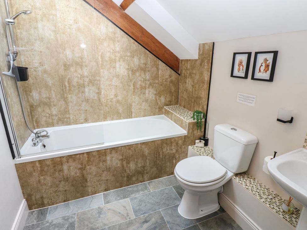 A bathroom featuring a shower, bathtub, toilet, and sink at Middlefell View Cottage in Alston