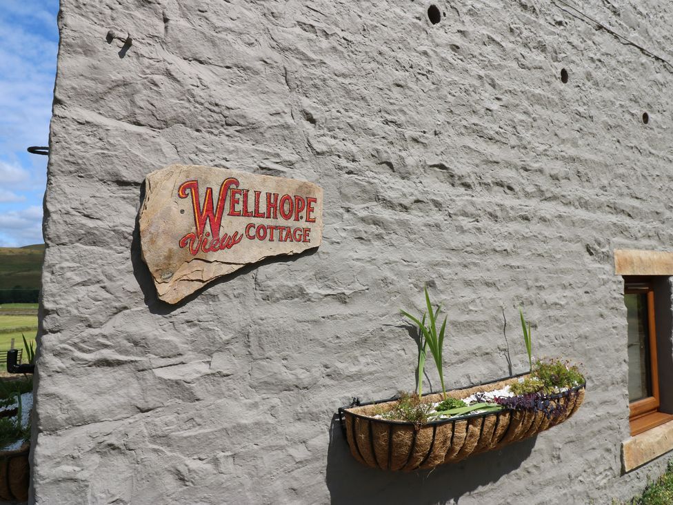 A sign reading Wellhope View Cottage on a stone wall at Wellhope View Cottage in Alston