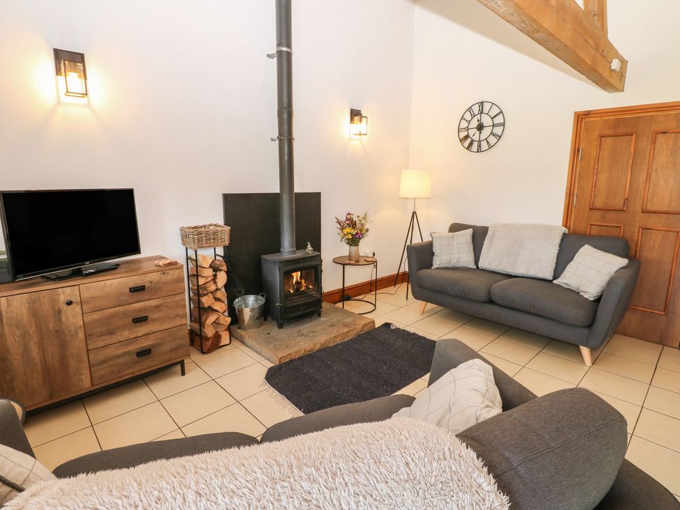 A living room with a wood stove and sofa at Wellhope View Cottage in Alston
