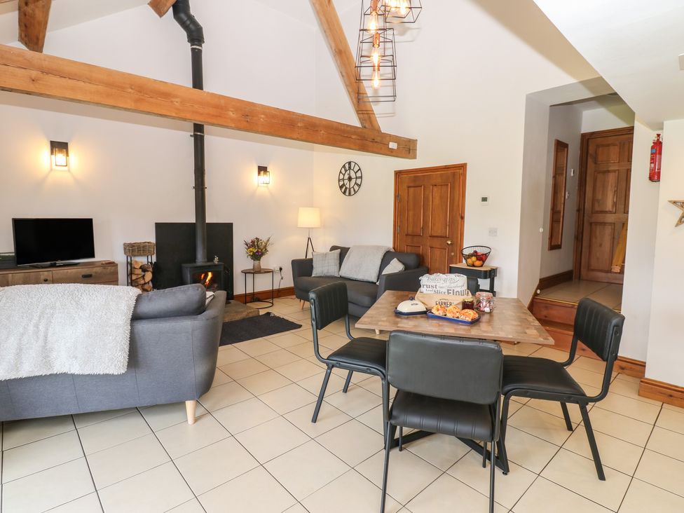 A living room with a wood stove and dining table at Wellhope View Cottage in Alston