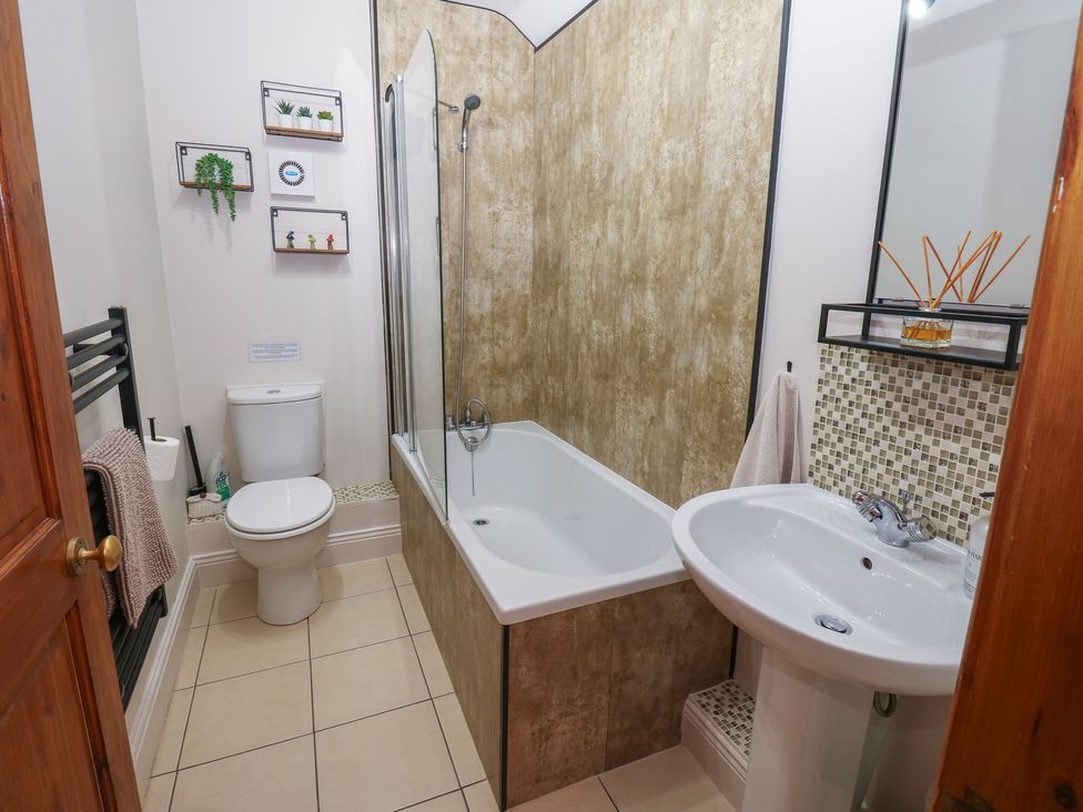 A bathroom with a bathtub, toilet, sink and towel rail at Wellhope View Cottage Alston