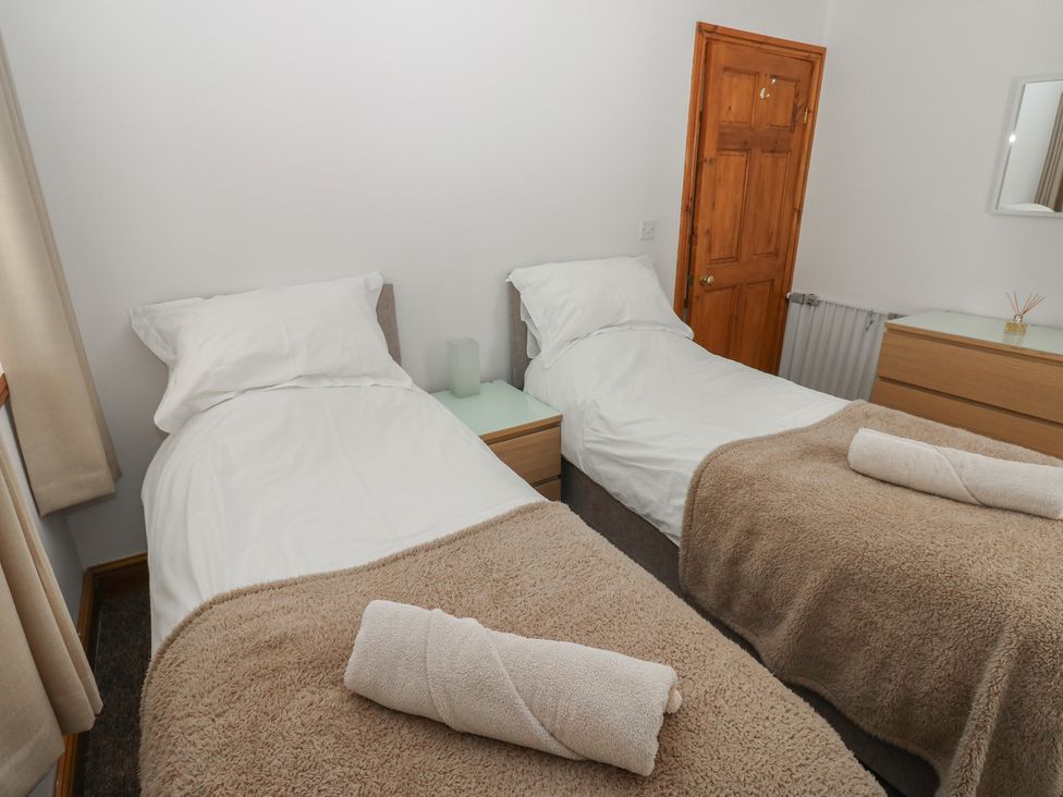 A bedroom with two single beds and a bedside table at Wellhope View Cottage Alston