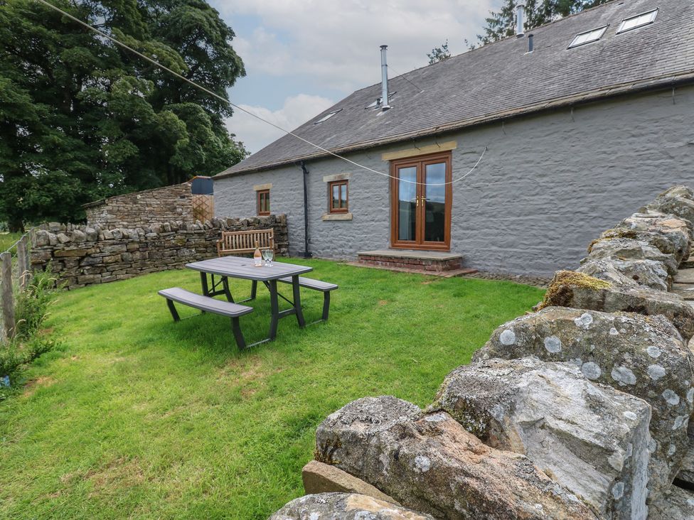 A garden with a table and bench at Wellhope View Cottage in Alston