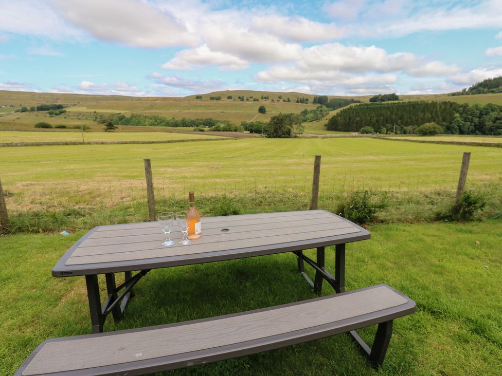 A table with wine and glasses in a garden at Wellhope View Cottage in Alston