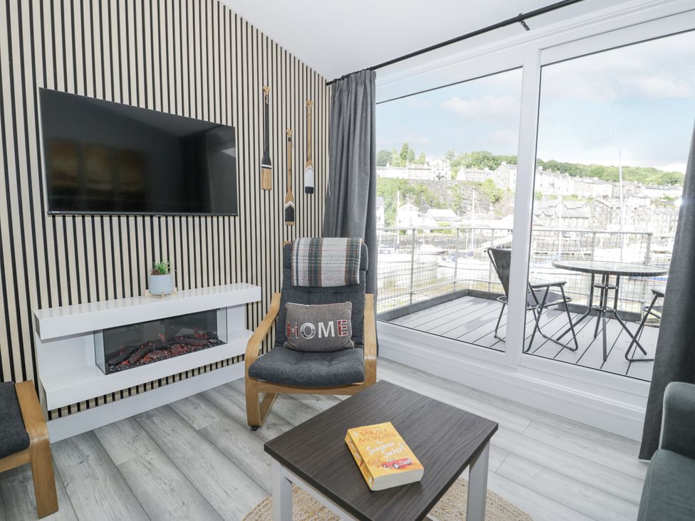 A living room with a television and fireplace at Harbwr Hideaway in Porthmadog