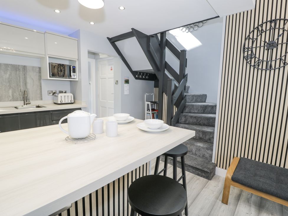 A kitchen with a staircase and dining area at Harbwr Hideaway in Porthmadog