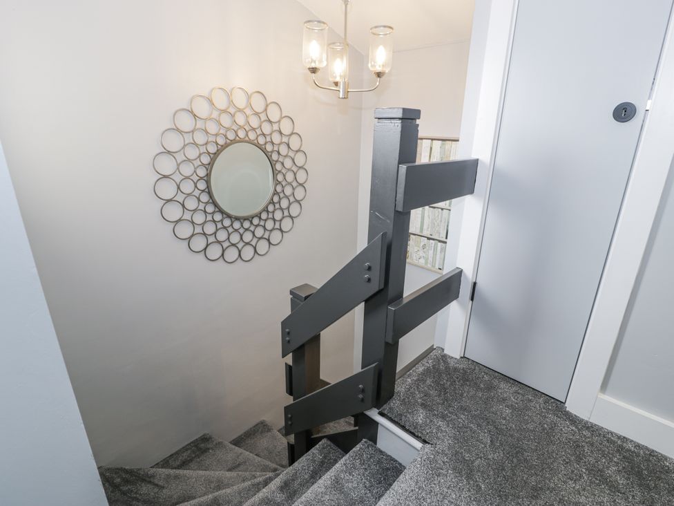 A staircase with a mirror and light fixture at Harbwr Hideaway in Porthmadog