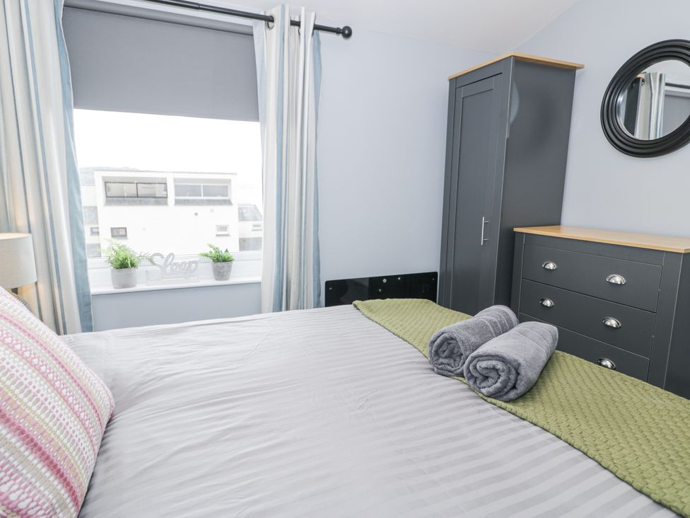 A bedroom with a bed, dresser and wardrobe at Harbwr Hideaway in Porthmadog