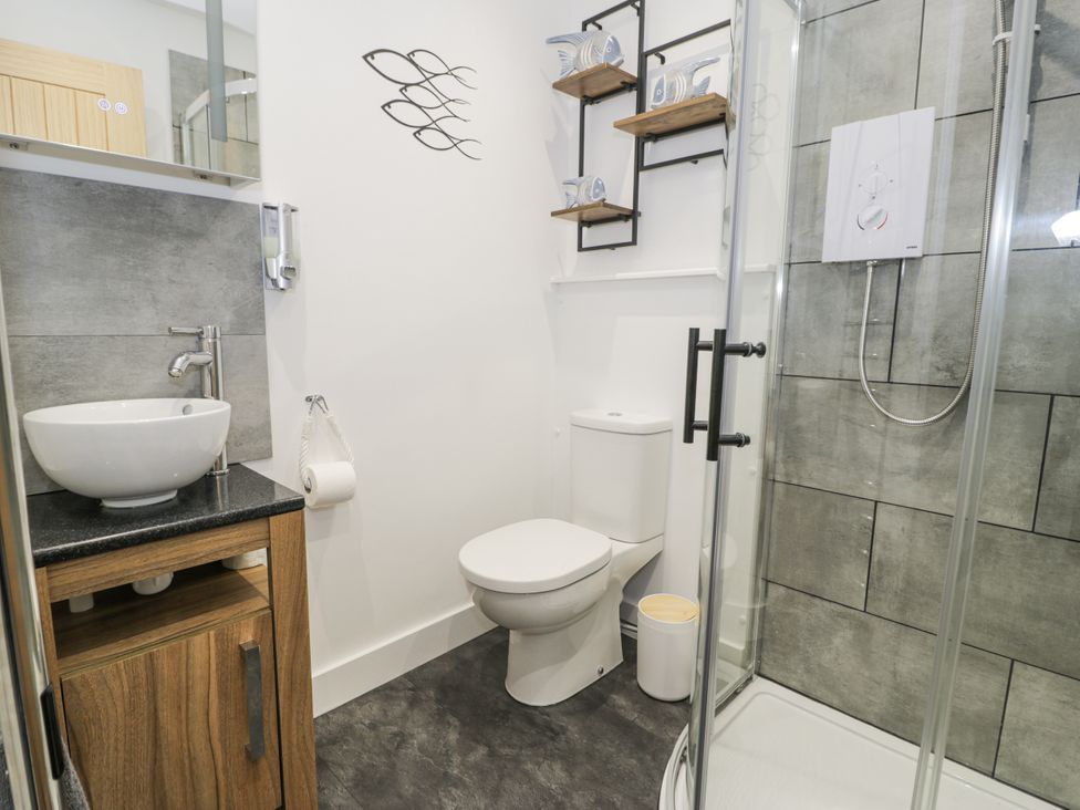 A bathroom with a sink, toilet, and shower at Harbwr Hideaway in Porthmadog
