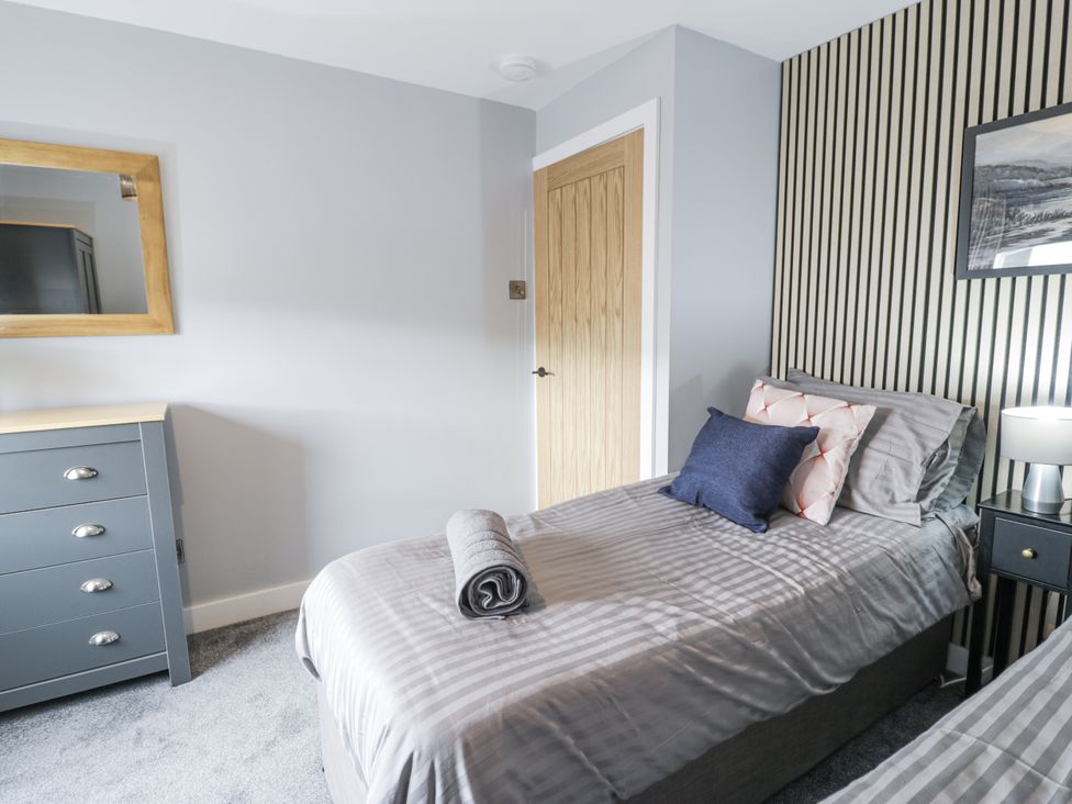 A bedroom with two beds and a mirror at Harbwr Hideaway in Porthmadog