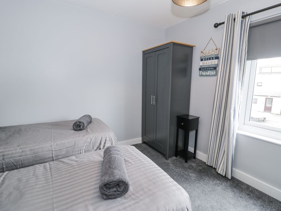 A bedroom with two beds and a wardrobe at Harbwr Hideaway in Porthmadog