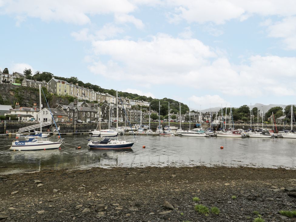 A marina with boats and buildings along the water at Harbwr Hideaway in Porthmadog