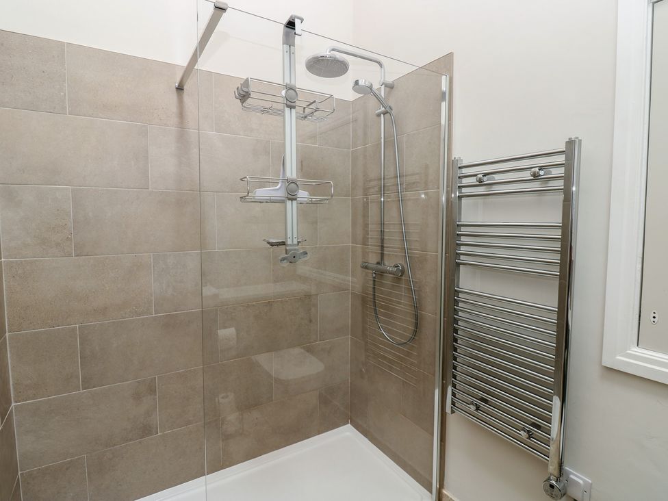 A shower enclosure with glass door and tiled wall at Antoninus Barn 2 Ebchester