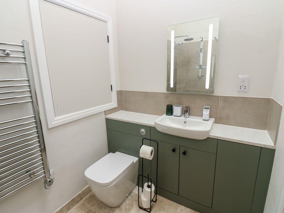A bathroom with a toilet, sink, mirror and towel warmer at Antoninus Barn 2 in Ebchester