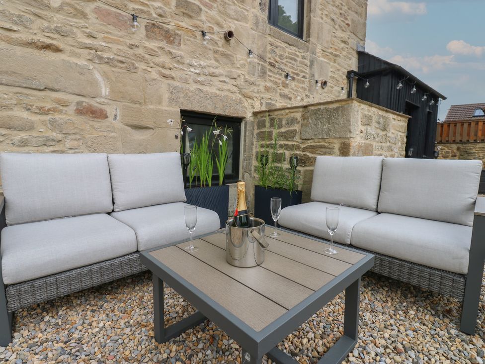 An outdoor seating area with a gray couch and table at Marcus Barn 3 Ebchester
